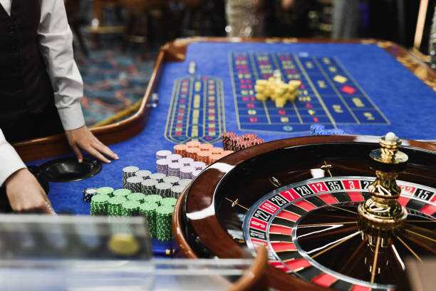 casino worker arranging roulette table for guests stacking gambling chips